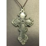 A carved green jade cross pendant on a thin cord thong.
