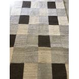 A wool rug with knitted square design in natural colours.