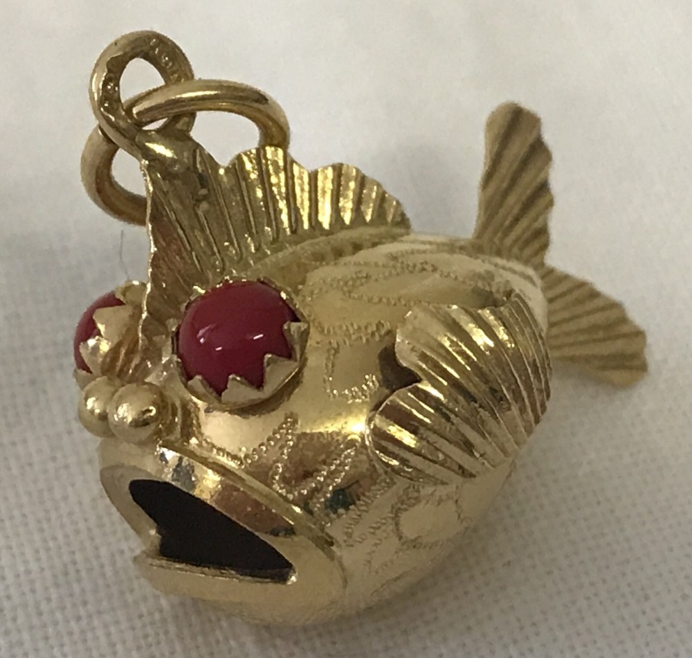 A 18ct gold fish charm with coral set eyes.