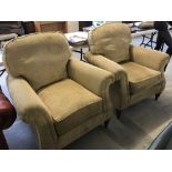 A pair of modern cream chenille armchairs with turned wooden feet.