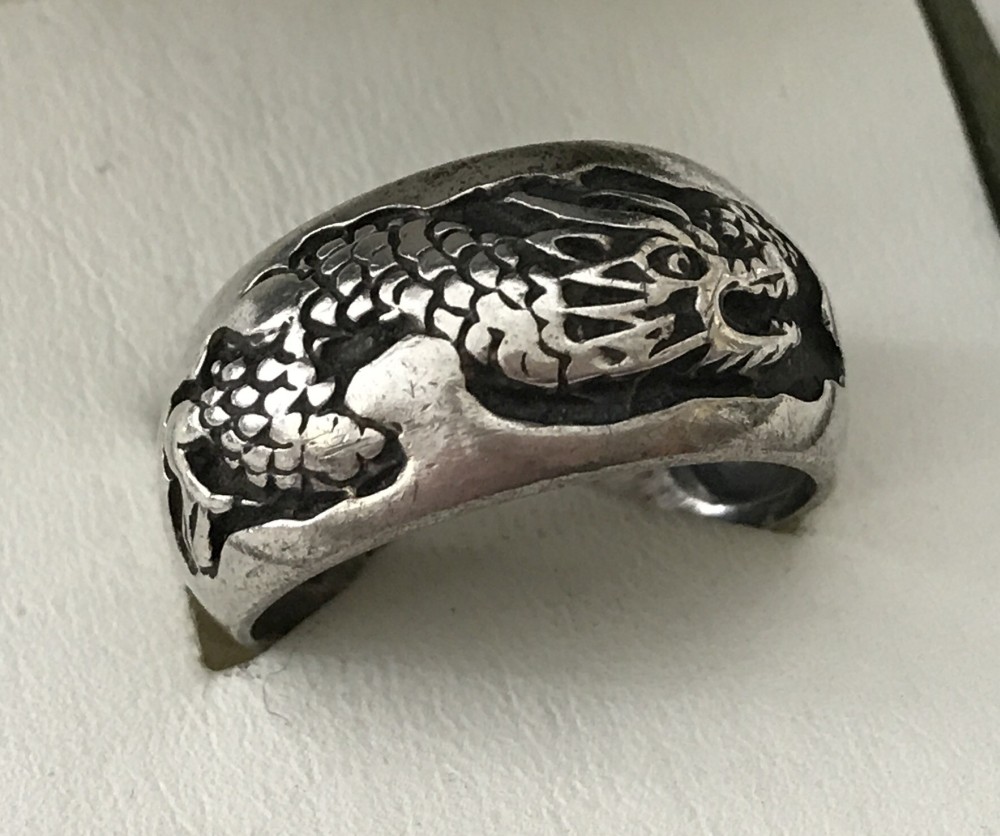 A men's silver band ring decorated with a oriental dragon.