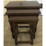 A dark wood nest of 3 tables with turned detail to legs.