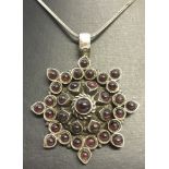 A large star shaped silver pendant sent with 33 round cut cabochon garnets.