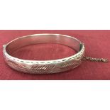 A Vintage silver bangle with half engraved detail and safety chain.