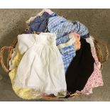 A wicker basket full of vintage dolls clothes.