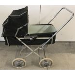A vintage toy dolls pram with brown fabric outer and cream plastic interior.