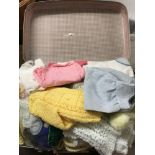 A vintage suitcase full of vintage dolls clothes.