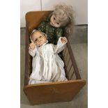 A vintage wooden dolls cot with 2 vintage vinyl and soft bodied dolls.