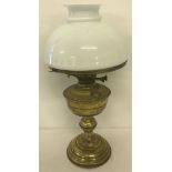 A vintage brass oil lamp with white glass shade and glass chimney.