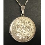 A vintage round silver locket with floral engraved decoration to front.