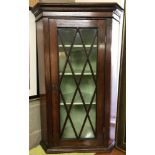 A dark oak corner cabinet with lattice style glazed door.