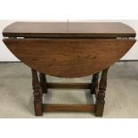 A small oak swivel top drop leaf table with turned legs.