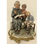 A Capodimonte group figurine of a grandmother reading to her grandchildren.