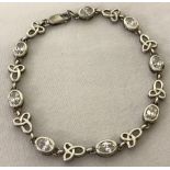 A decorative silver bracelet with Celtic knot link and bezel set white stone links.
