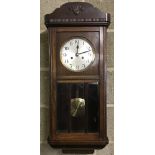 A vintage dark wood cased wall hanging pendulum clock.