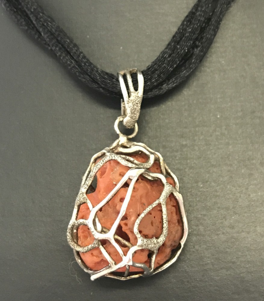 A contemporary design pendant made from natural coral decorated with silver.