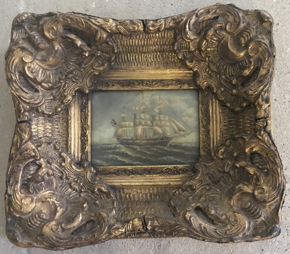 A modern ornately framed oil over print of a tall ship.