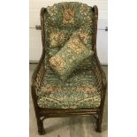 A conservatory style arm chair with William Morris style upholstery in green and gold.