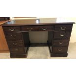 A reproduction mahogany pedestal desk with green leather writing surface.