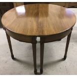 A vintage circular dining table which separates into 2 half moon occasional tables.