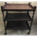 A vintage dark wood 3 tier tea trolley with barley twist columns.