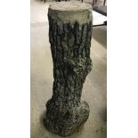 A concrete garden pedestal in the shape of a tree trunk.