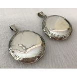 2 large round silver lockets with engraving to outer edge.