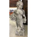 A concrete garden ornament of a classical style girl carrying a basket of flowers.