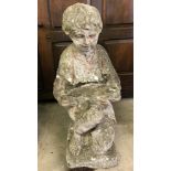 A concrete garden ornament of a young boy kneeling.