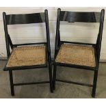 2 wooden framed, cane seated folding chairs.