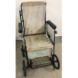 A vintage metal framed invalid chair with canvas material seating.