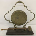 A vintage table top brass gong with beater on wooden plinth.