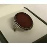 A silver dress ring set with large oval carnelian stone.