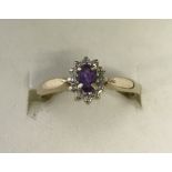 A 9ct gold dress ring set with central amethyst surrounded by 11 small diamonds.