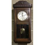 A vintage dark wood cased wall hanging pendulum clock.