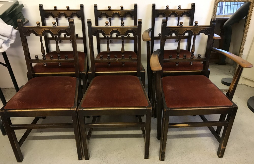 A set of 6 dark wood dining chairs with rust coloured upholstered seats and turned spindle backs.