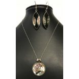 A large pendant set with paua/abalone shell and a garnet in a decorative silver mount,