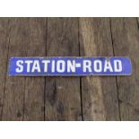 An enamel rectangular blue and white "STATION ROAD" sign,