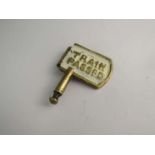 A brass single line key token with "TRAIN ON LINE" and "TRAIN PASSED" on each sides