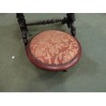 A Victorian mahogany footstool with tan floral upholstery,