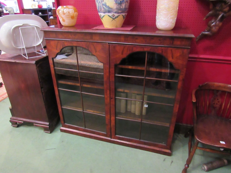 An 18th Century style figured walnut two door glazed bookcase on a plinth base (with key)