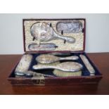 A cased set of silver dressing table items including hair brushes, mirror, pin trays,