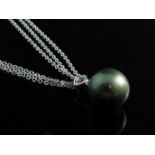 A modern large black pearl pendant hung from two graduated diamonds together with long slender