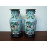 A pair of 20th Century Chinese vases with warrior/battle scene cartouches on wooden base,