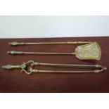 An ornate 19th Century brass three piece fire companion set with floral detail