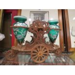 A Victorian carved table centre-piece in the form of a wagon, aloft a pair of green opaque vases,