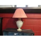 A large urn shaped pottery lamp base with pink pleated shade