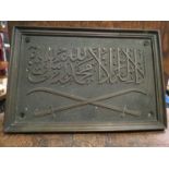 A bronze Arabic plaque with crossed sword and script