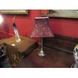 A brushed brass table lamp with fluted column and burgundy/gold shade