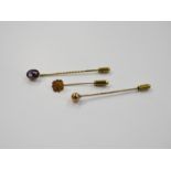 Three stick pins including one amethyst yellow metal